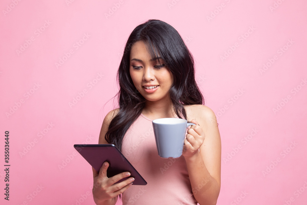 Young Asian woman with a computer tablet and coffee. Young Asian woman with a computer tablet and coffee.
