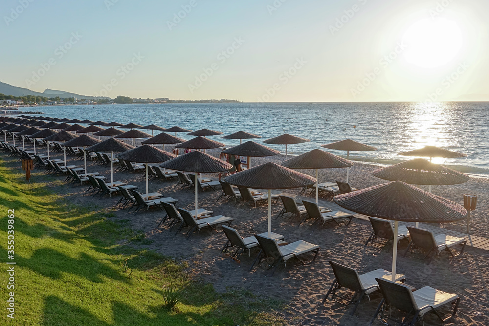 Φωτογραφία Sun beds and umbrellas on the sea coast at sunset.