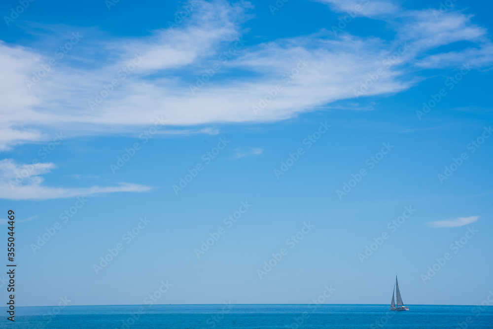 Calm sea with sailboat on the horizon. Blue sky seascape with copy space.