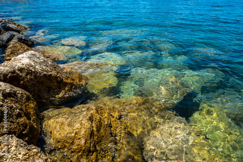 Shore of large rocks and clear sea water on a sunny day