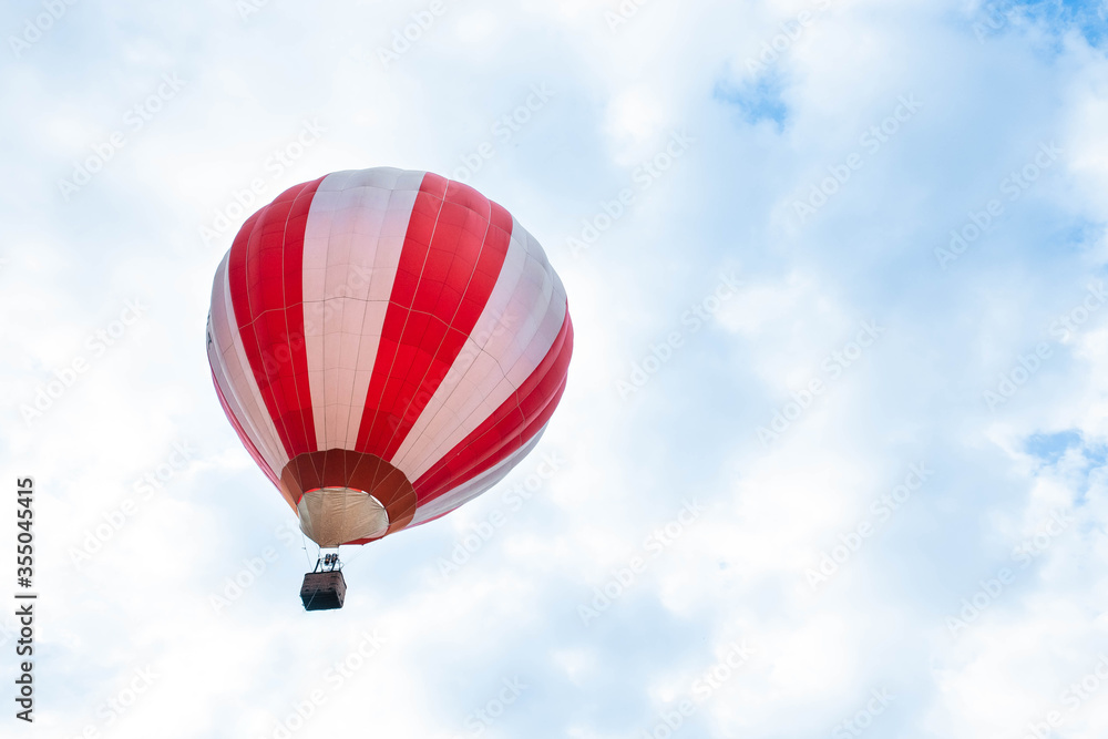 Naklejka premium Balloon in the blue sky. Red balloon in the blue cloudy sky.