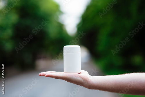 Man's hand shows a medical bottle with pills isolated on the background. Close. High resolution product. Hand holds a white plastic bottle.