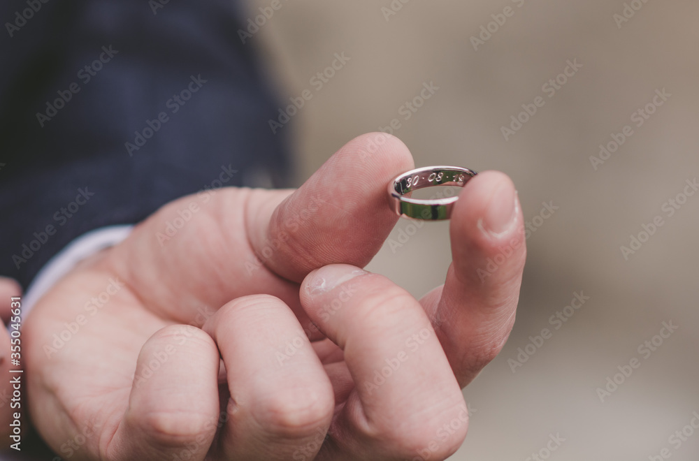 Man/Groom holds wedding ring in hand