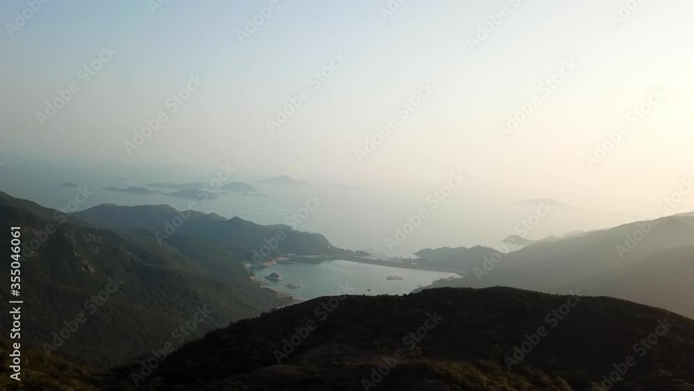 Aerial panning shot of sea and mountains against clear sky, drone flying over natural landscape - Hong Kong, China Aerial panning shot of sea and mountains against clear sky, drone flying over natural landscape - Hong Kong, China