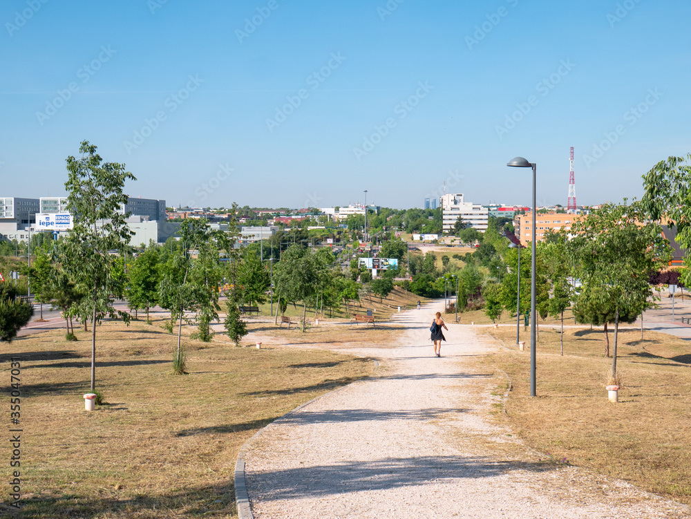 Obraz premium People walking and playing sports on the path of a park during the coronavirus alarm state. Near the Infanta Sofia hospital