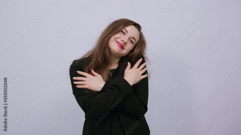 Young Attractive Woman Brunette In In A Black T-Shirt, Sweater On White Background, Cute Female Puts Hands On Her Chest, Smiles. The Concept Tenderness And Mercy Of People Young Attractive Woman Brunette In In A Black T-Shirt, Sweater On White Background, Cute Female Puts Hands On Her Chest, Smiles. The Concept Tenderness And Mercy Of People
