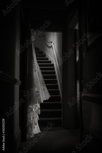 Wedding dress hangs in dark hallway
