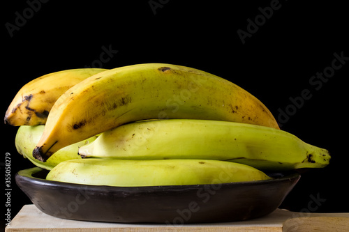 Plantain or Green Banana (Musa x paradisiaca) in a ceramic traditional dish on dark background