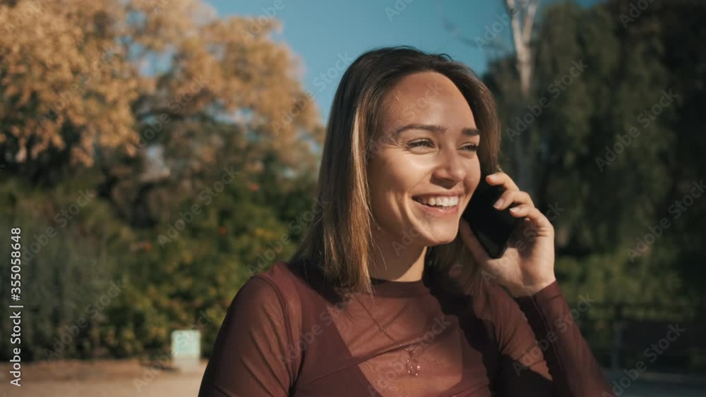 Attractive cheerful girl happily laughing talking on the phone with boyfriend in city park. Beautiful blond girl flirting on the phone Attractive cheerful girl happily laughing talking on the phone with boyfriend in city park. Beautiful blond girl flirting on the phone