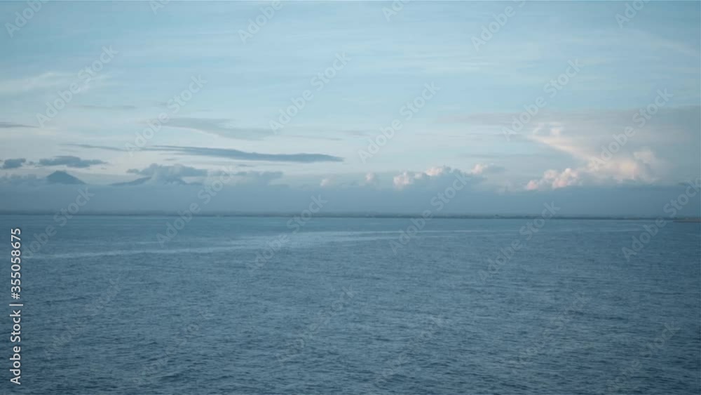 Marine landscape with blue clear water, clouds and volcanoes on the horizon Marine landscape with blue clear water, clouds and volcanoes on the horizon