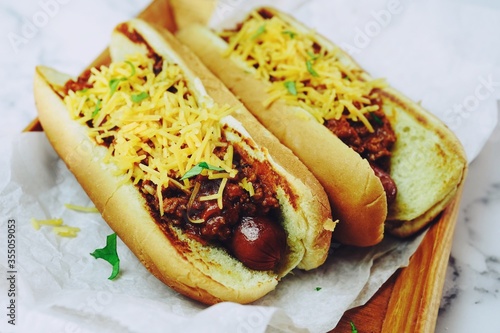 Homemade Chili dogs topped with cheddar cheese, selective focus