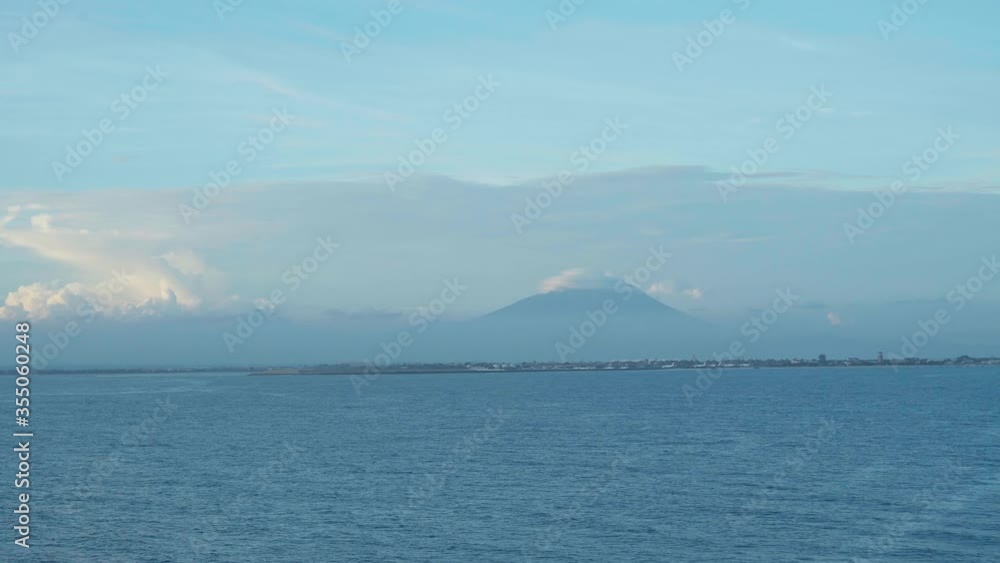 Marine landscape with blue clear water, clouds and volcanoes on the horizon Marine landscape with blue clear water, clouds and volcanoes on the horizon