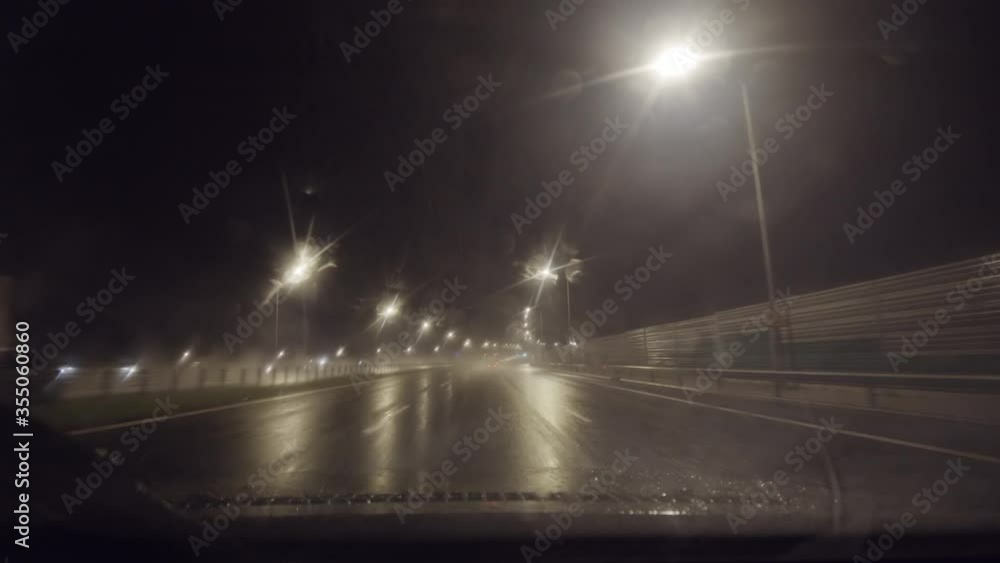 Timelapse fast highway driving, heavy rain at night. First person view of driving a car on highway with windshield working at full speed. Timelapse fast highway driving, heavy rain at night. First person view of driving a car on highway with windshield working at full speed.