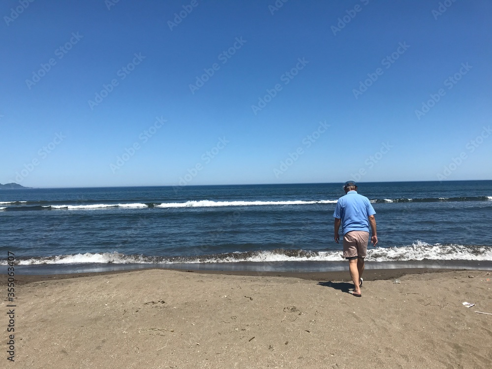 海に向かって歩く男性