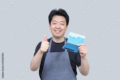 Fotografia A middle-aged Asian man holding a bank passbook in his hand on a gray background
