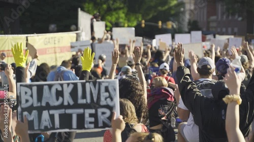 Black Lives Matter protesters kneeling holding hands up photo