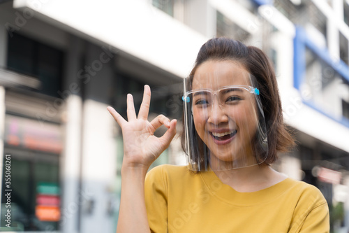 Portrait happy woman wile wearing a face shield for protection from cold and flu and viruses. Young woman with face mask in the street. Woman wearing face mask because of air pollution in the city