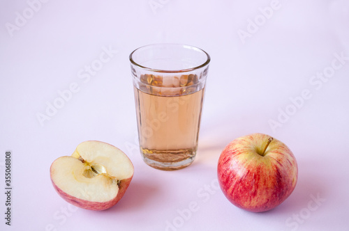Whole and cut red Apple and a glass of Apple juice on a pink background