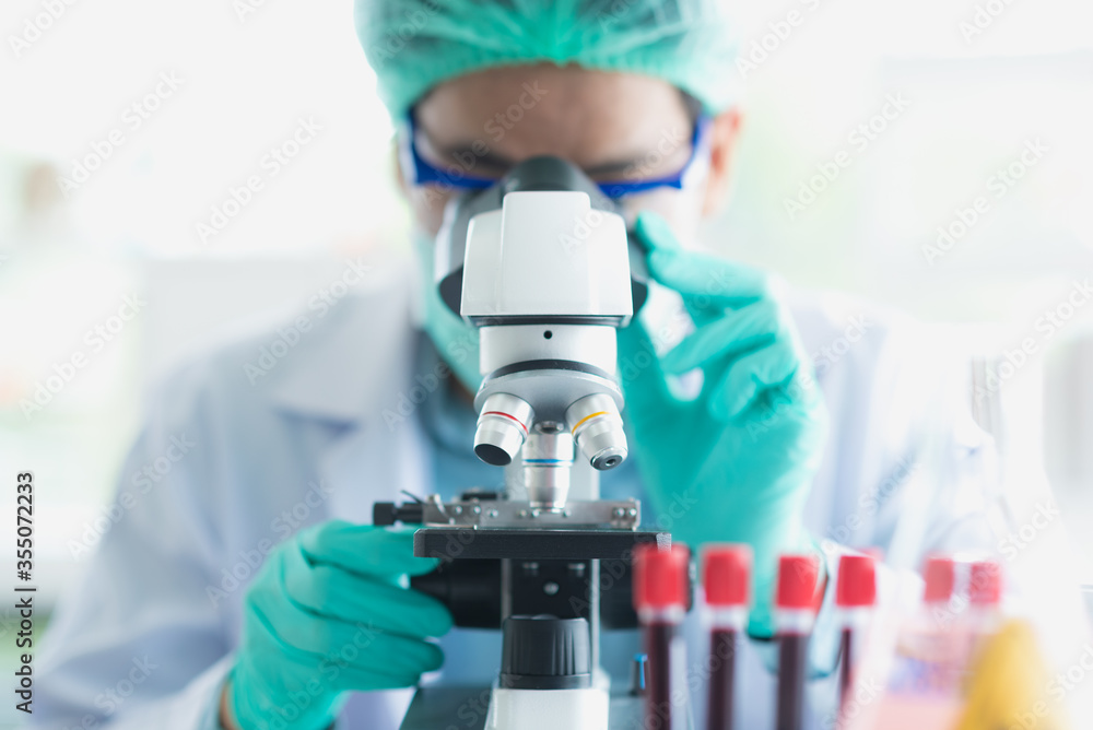 Professional Asian scientist or researcher man in work coat uniform using microscope to looking and analyzing sample in science lab Professional Asian scientist or researcher man in work coat uniform using microscope to looking and analyzing sample in science lab