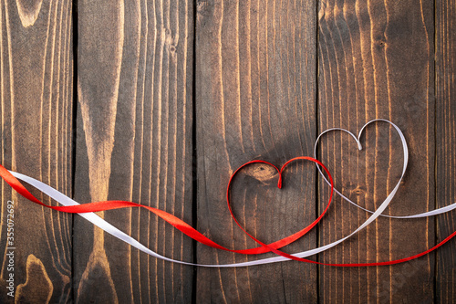 Red and white hearts on a dark wooden background. Background to the day of St. Valentine