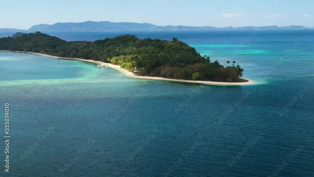 Drone shot of Port Barton with white sand coastline middle of blue sea and mountains in far BG;sunlight falling on trees gives serene feeling Drone shot of Port Barton with white sand coastline middle of blue sea and mountains in far BG;sunlight falling on trees gives serene feeling