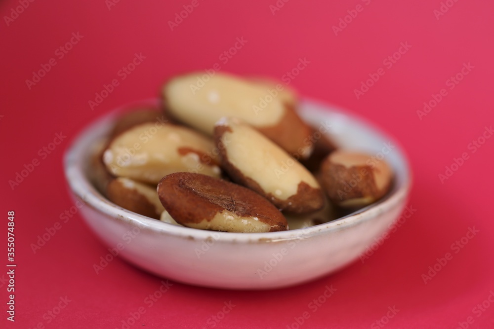 Brazil nut in a ceramic gray cup on a bright pink background. Wholesome food and snack. Healthy fats ingredient. Vegetarian and vegan food.keto diet. Brazil nut in a ceramic gray cup on a bright pink background. Wholesome food and snack. Healthy fats ingredient. Vegetarian and vegan food.keto diet.