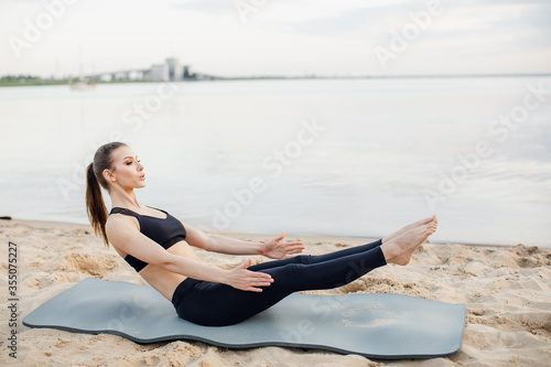 fitness model goes in for sports on the beach. Does abdominal exercises