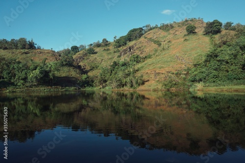 Landscape view of a hill and lake with clear blue skies. © rifky