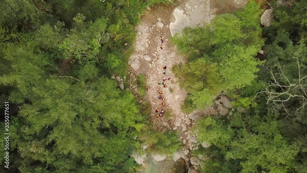Aerial top down shot of people canyoning in a rocky river surrounded by vegetation. Sadernes, Spain. Aerial top down shot of people canyoning in a rocky river surrounded by vegetation. Sadernes, Spain.