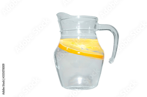 Clear liquid in a clear pitcher with orange pieces inside isolated on white background