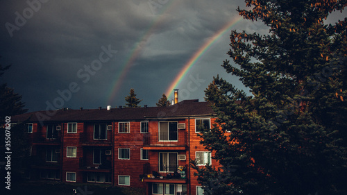 Rainbow coming out from canadian red house during harsh sunlight with black background. photo