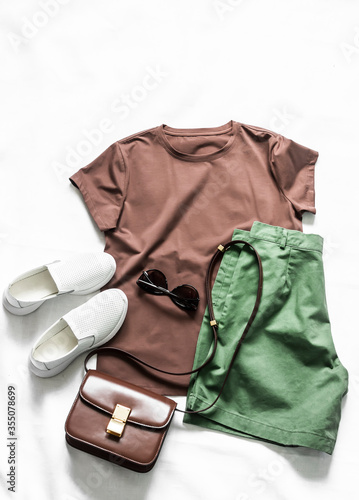 Women's cotton bermuda shorts, brown t-shirt, cross body bag, white sneakers on a light background, top view