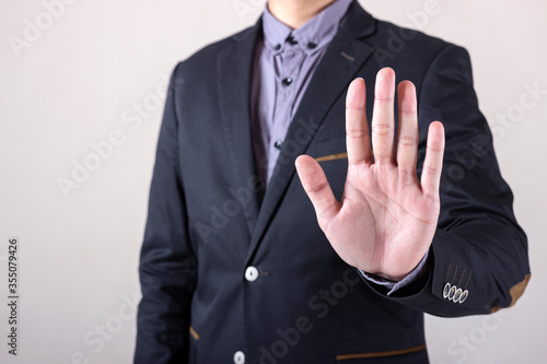 Man in business suit showing hand palm or stop gesture, concept of rejection and refusal.