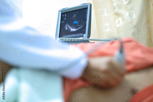 Physician making echocardiography for male patient heart, focus screen of echocardiography machine