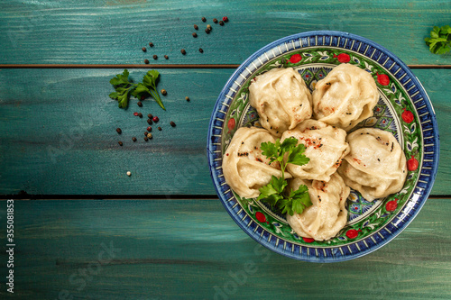 Uzbek prepared boiled Manti or manty dumplings in a traditional bowl on wooden table. banner menu recipe place for text photo