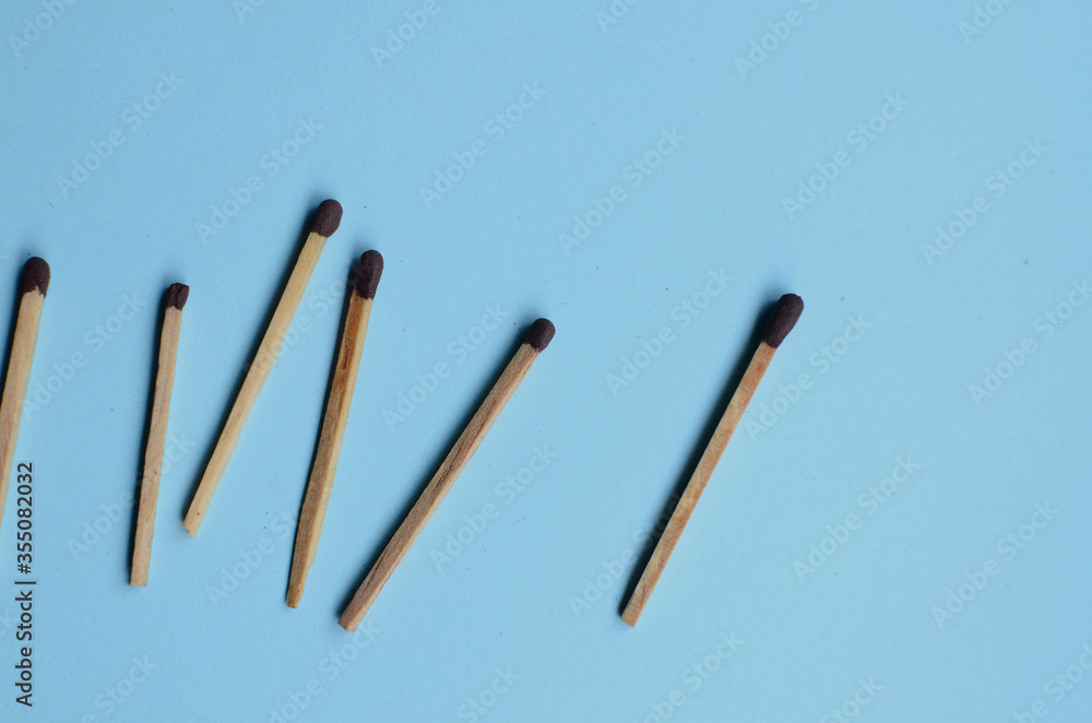 Scattered matches stick on a blue background with copyspace. Top view.
Scattered matches stick on a blue background with copyspace. Top view.