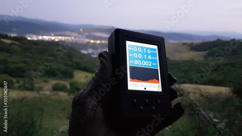 Geiger Counter Radiation Measurement Against Human Settlement At Dusk photo