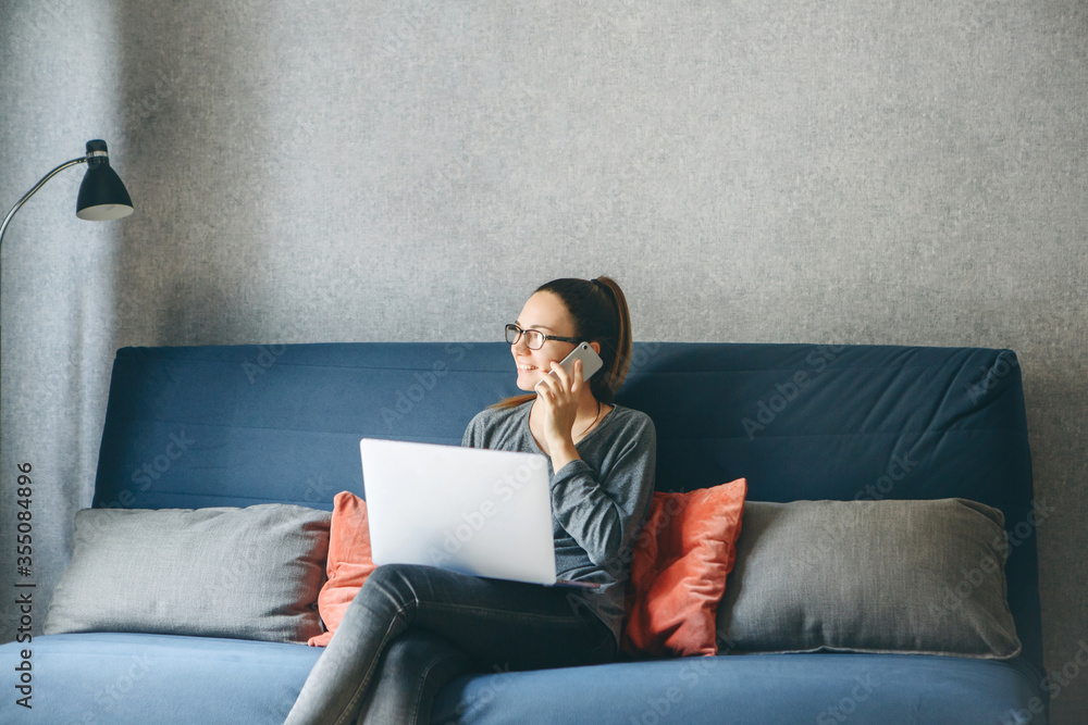 A girl works from home or a student is studying from home or a freelancer. She uses a laptop and a phone. A girl works from home or a student is studying from home or a freelancer. She uses a laptop and a phone.