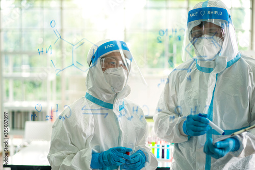 Asian scientist and medical staff in ppe suit analyzing and researching a sample of coronavirus vaccine  in virus laboratory. coronavirus, vaccination, virus laboratory  or microbiologist concept