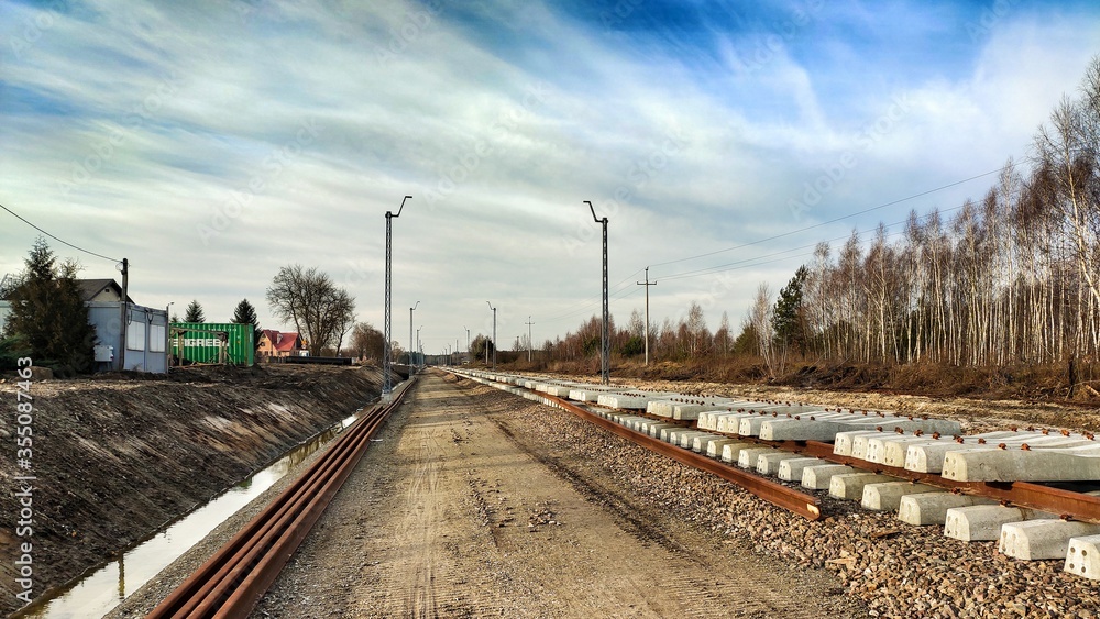 Zabiezki, Poland, 2020. View on railway line construction site in small village near Otwock and Warsaw. Railway components ready to deploy. Train tracks underlay and concrete ties.