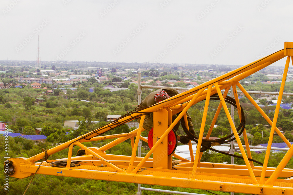 The technician removing tower crane from rooftop by derrick crane.