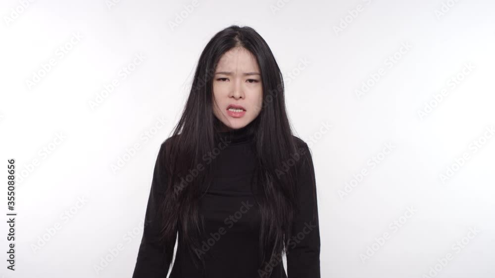 Portrait of a woman of Asian descent feeling frustrated, clenching her fists and screaming with anger Portrait of a woman of Asian descent feeling frustrated, clenching her fists and screaming with anger