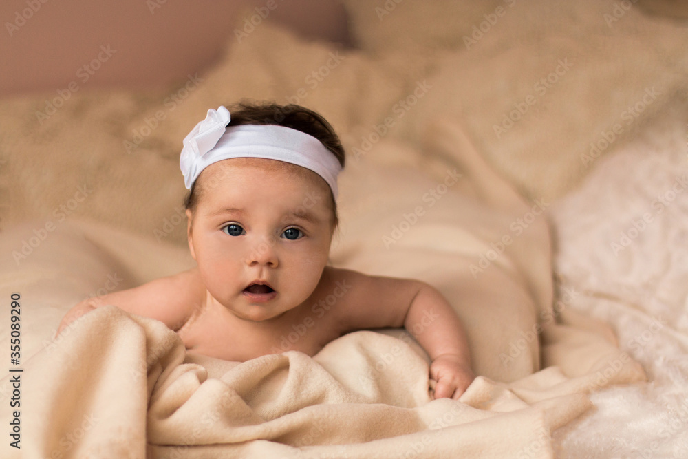 Portrait of adorable smiling newborn baby with thick brown hair . Nude newborn child relaxing in bed. Portrait of adorable smiling newborn baby with thick brown hair . Nude newborn child relaxing in bed.