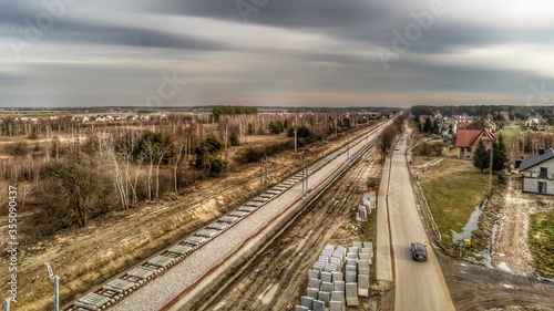 Zabiezki, Poland, 2020. Aerial view on railway line construction site in small village near Otwock and Warsaw. Railway components ready to deploy. Train tracks underlay and concrete ties.