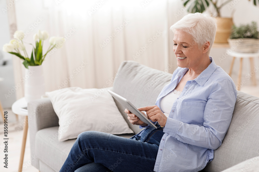 Elderly Woman Spending Time With Digital Tablet On Couch In Living Room Elderly Woman Spending Time With Digital Tablet On Couch In Living Room