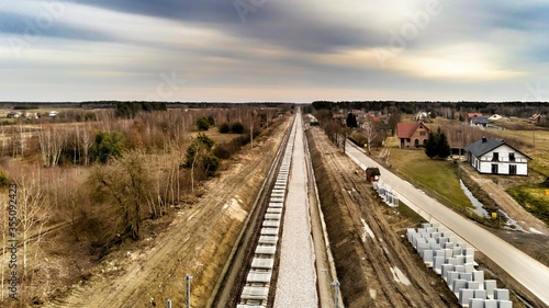 Zabiezki, Poland, 2020. Aerial view on railway line construction site in small village near Otwock and Warsaw. Railway components ready to deploy. Train tracks underlay and concrete ties.