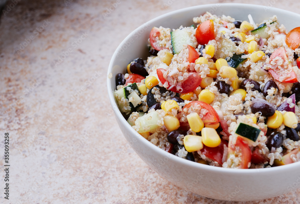 Healthy vegan quinoa bowl salad. Tomato, black beans, sweet corn and cucumber.