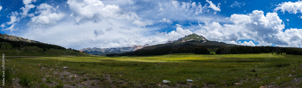 panorama of colorado mountains and green meadow