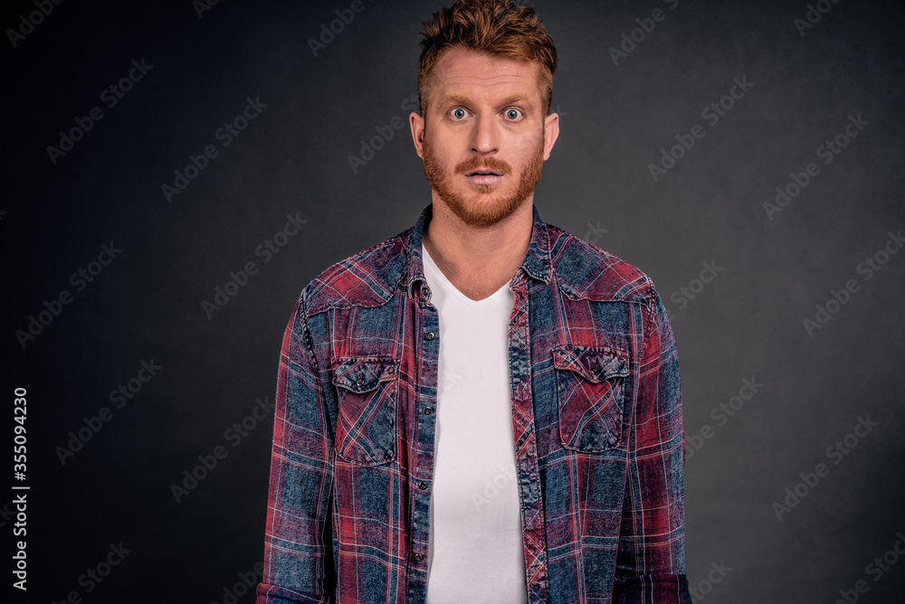 Waist-up shot of attractive masculine macho man with ginger hair in checkered shirt and gazing with confident and self-assured expression at camera, feeling calm and ready to work Waist-up shot of attractive masculine macho man with ginger hair in checkered shirt and gazing with confident and self-assured expression at camera, feeling calm and ready to work