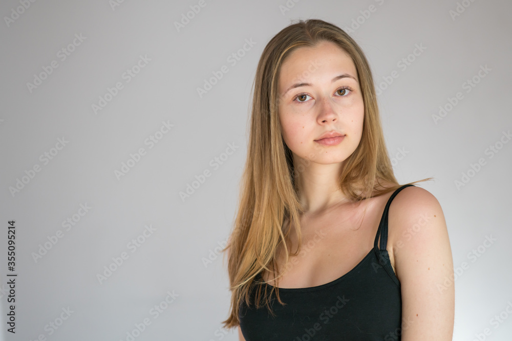 Obraz premium Portrait of an attractive teenage girl wearing a camisole posing looking at the camera on grey background